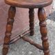 Low wooden tripod stool.