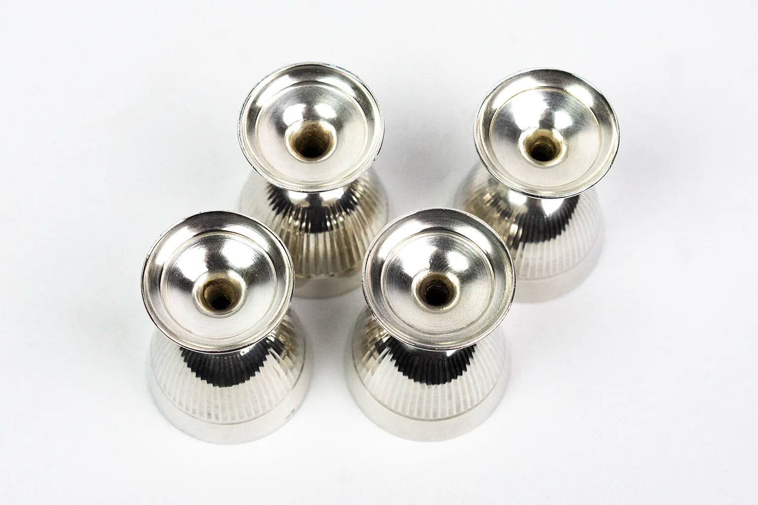 Four silver-plated Christofle egg cups with fluted sides.