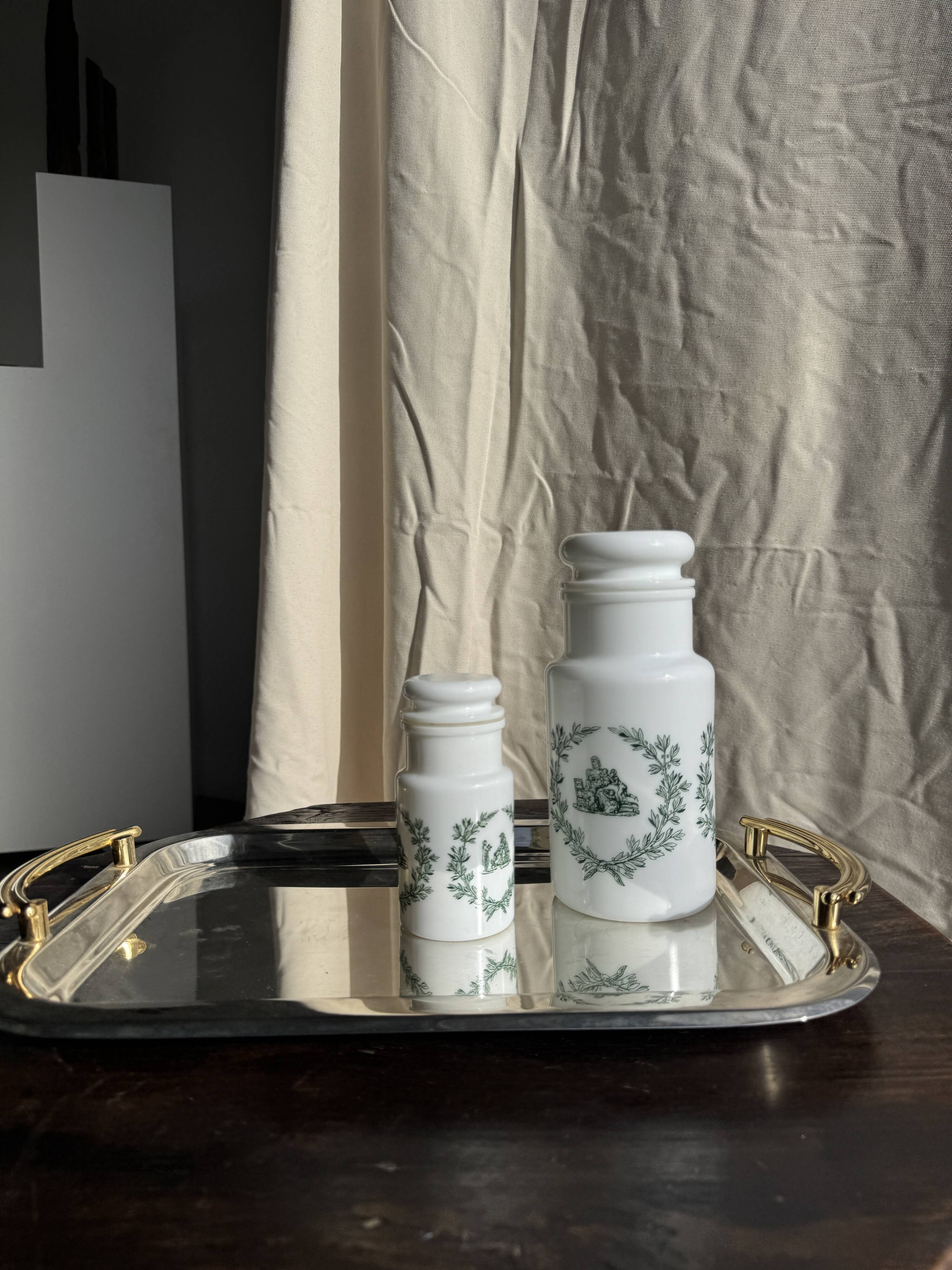 A pair of white glass bottles with Italian green patterns.