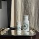 A pair of white glass bottles with Italian green patterns.