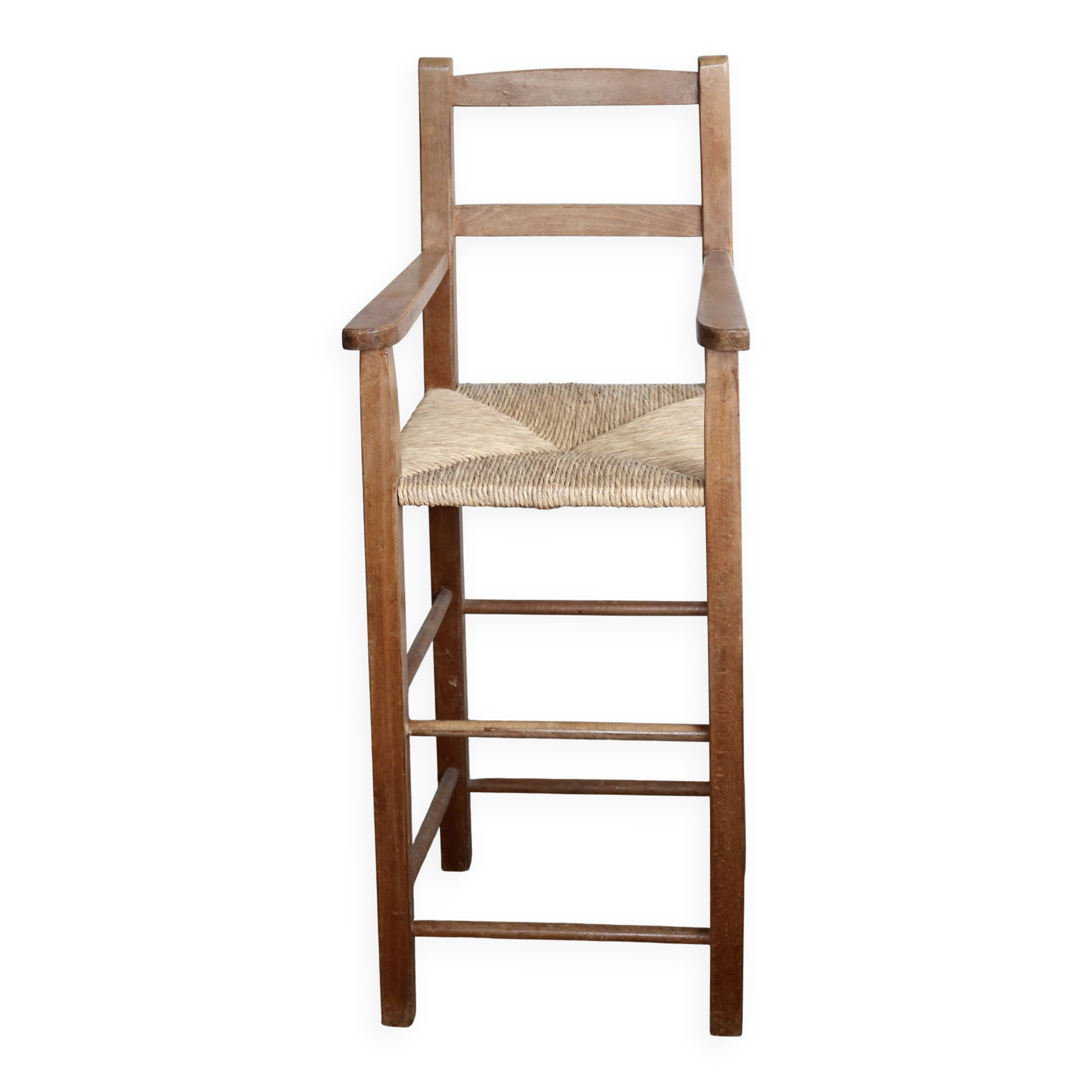 Vintage wooden high chair for children with a straw seat.
