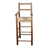 Vintage wooden high chair for children with a straw seat.