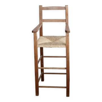 Vintage wooden high chair for children with a straw seat.