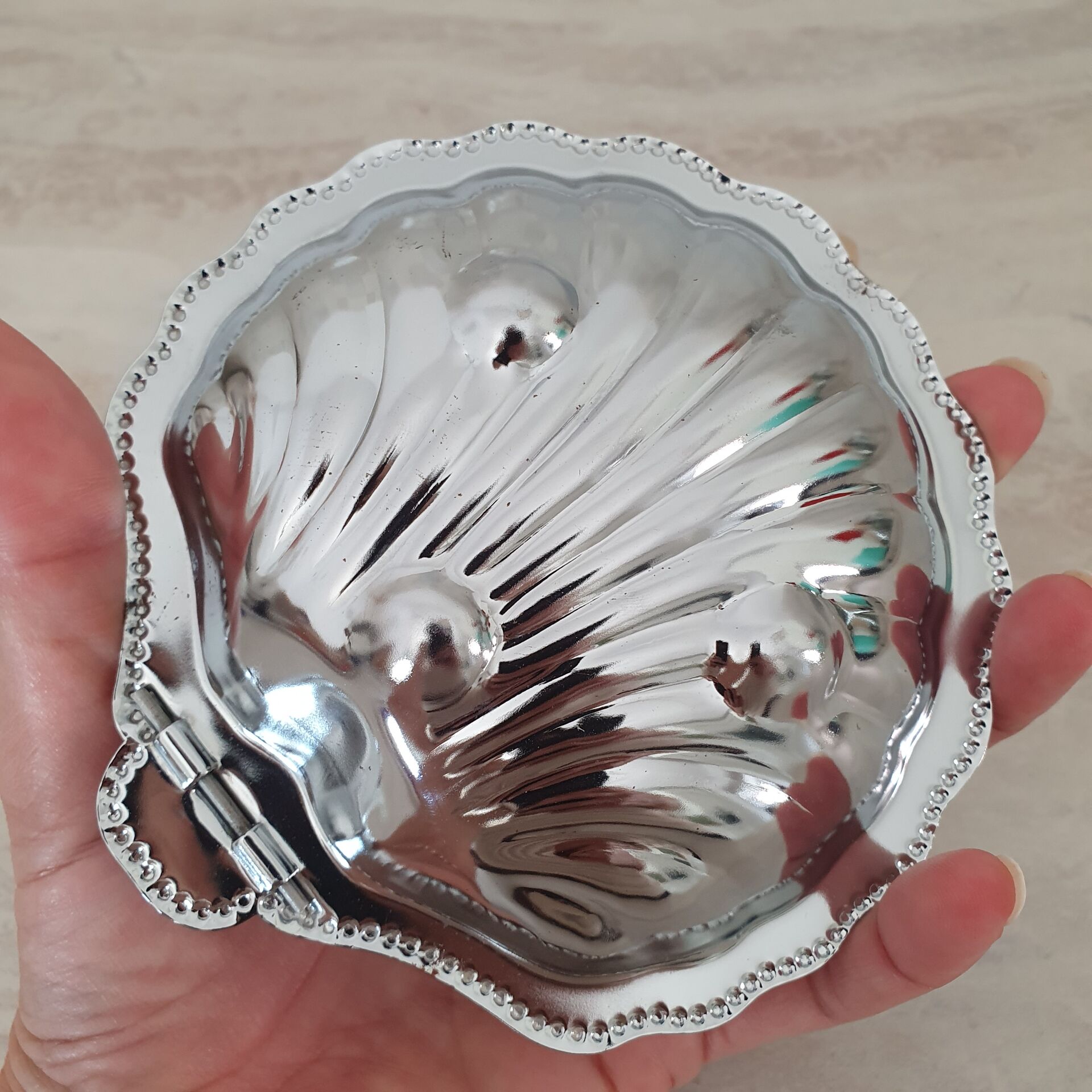 Shell-shaped butter dish in stainless steel and white glass bowl.