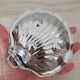 Shell-shaped butter dish in stainless steel and white glass bowl.