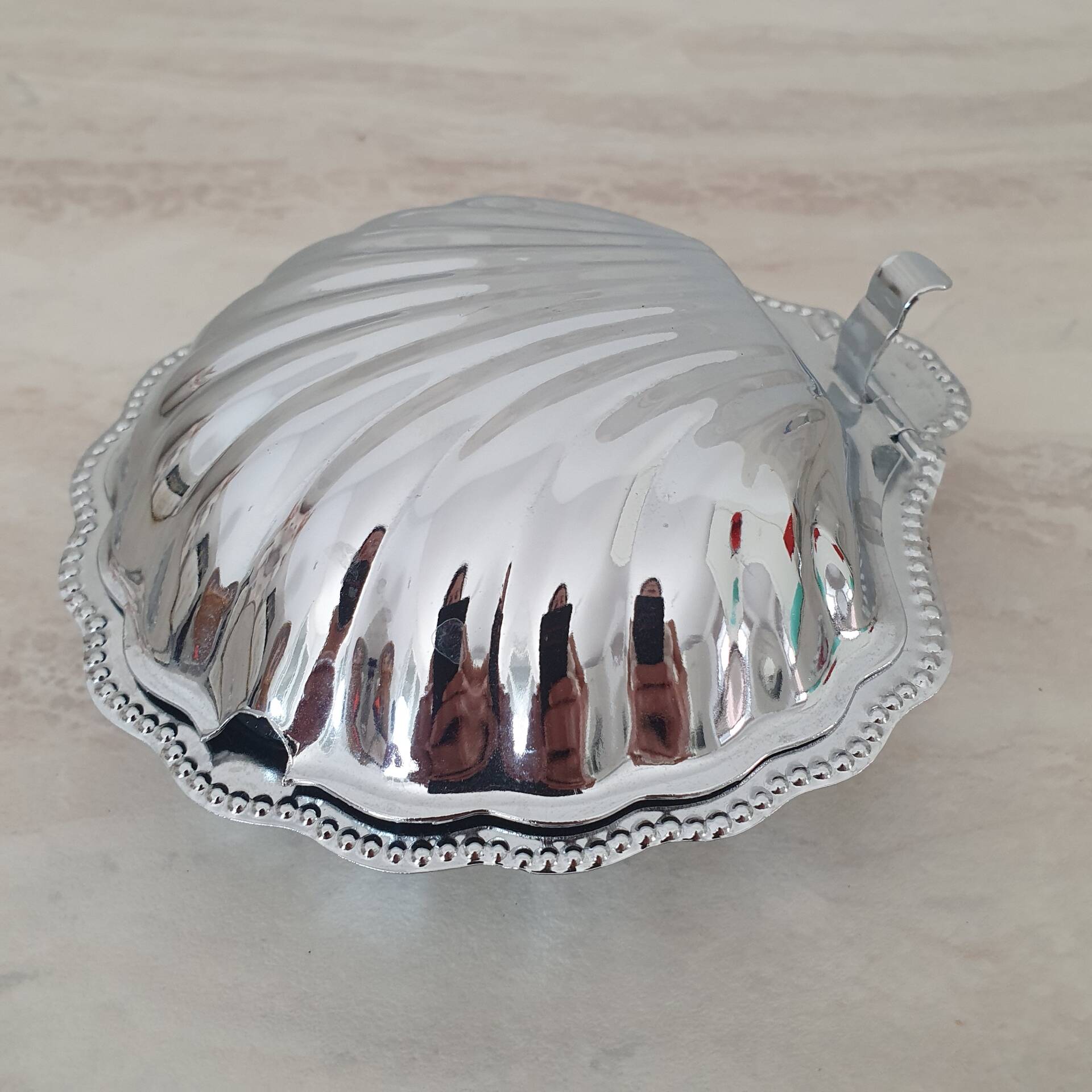 Shell-shaped butter dish in stainless steel and white glass bowl.