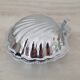 Shell-shaped butter dish in stainless steel and white glass bowl.
