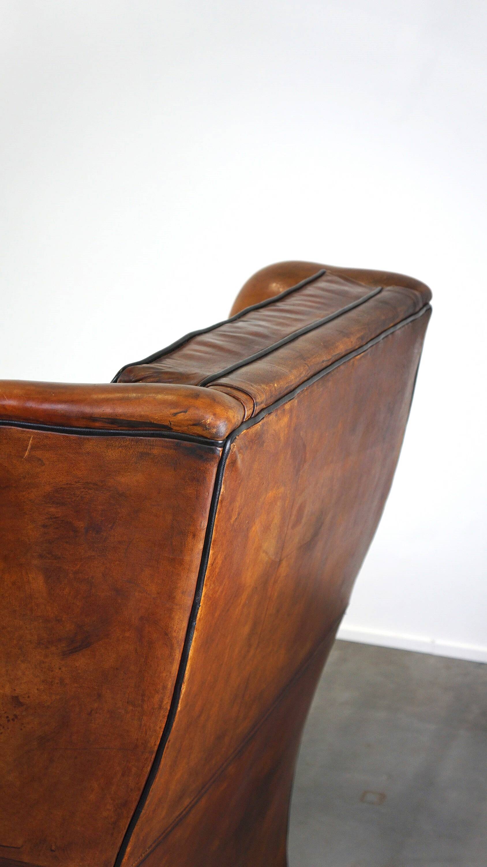 Very large worn sheepskin wing chair with a checked seat cushion