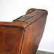 Very large worn sheepskin wing chair with a checked seat cushion