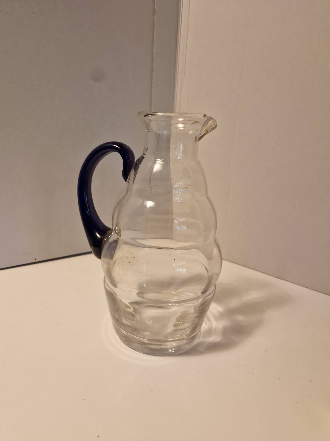 Glass carafe with wavy body and blue handle