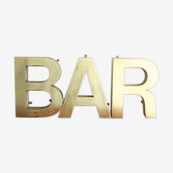 Old brass sign letters, word BAR