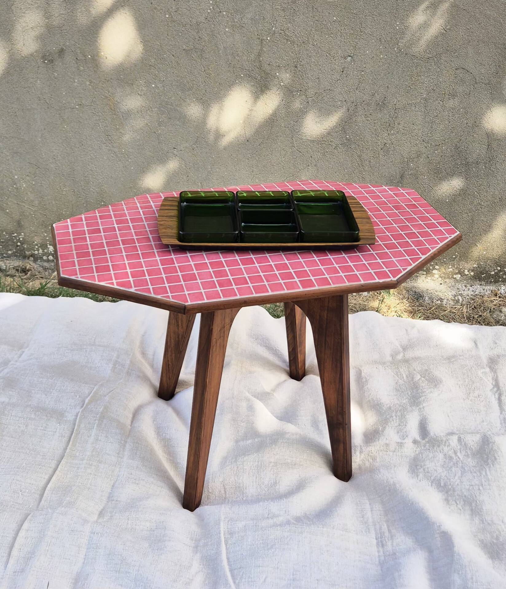 Small Scandinavian side table with wood and pink tiles, with tapered legs.