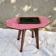 Small Scandinavian side table with wood and pink tiles, with tapered legs.