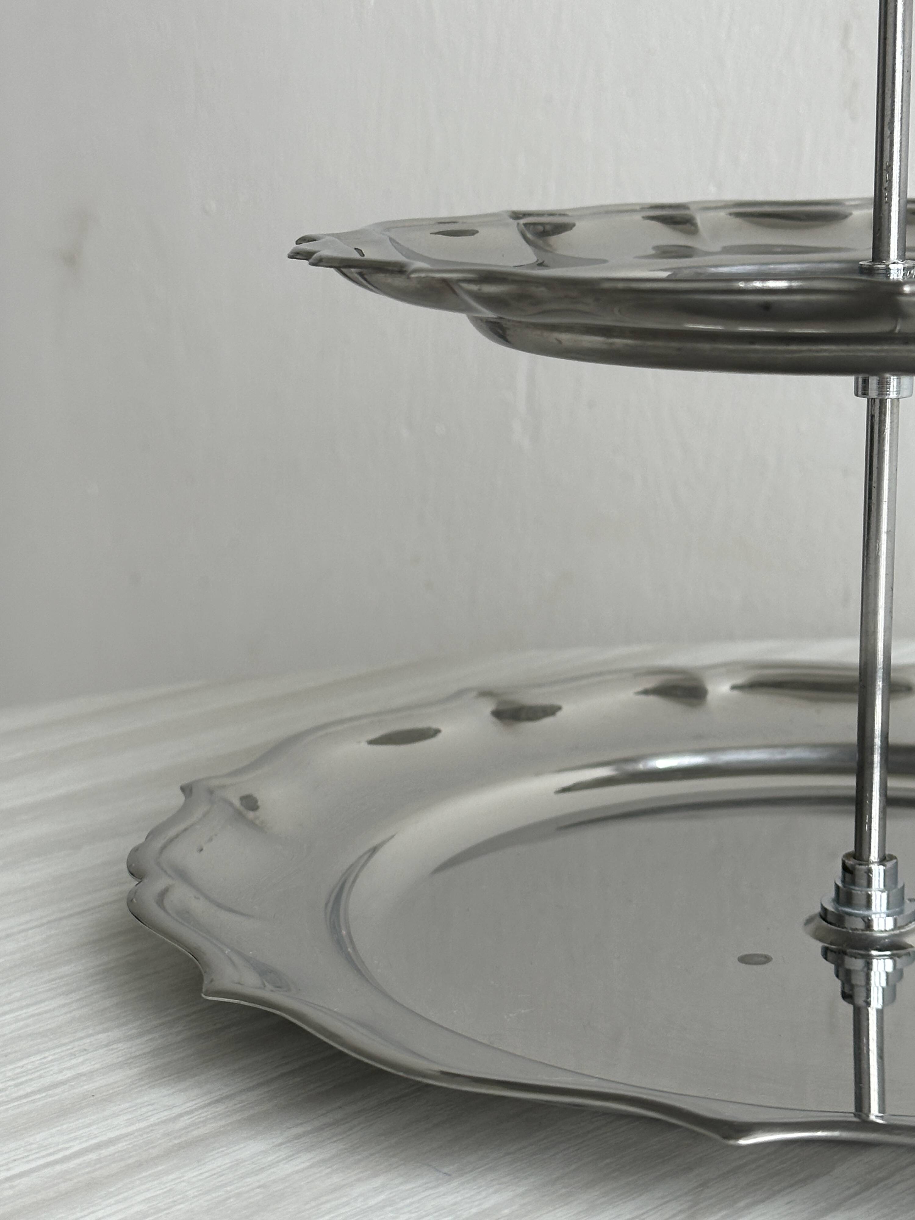 Three-tiered serving trolley in shiny stainless steel.