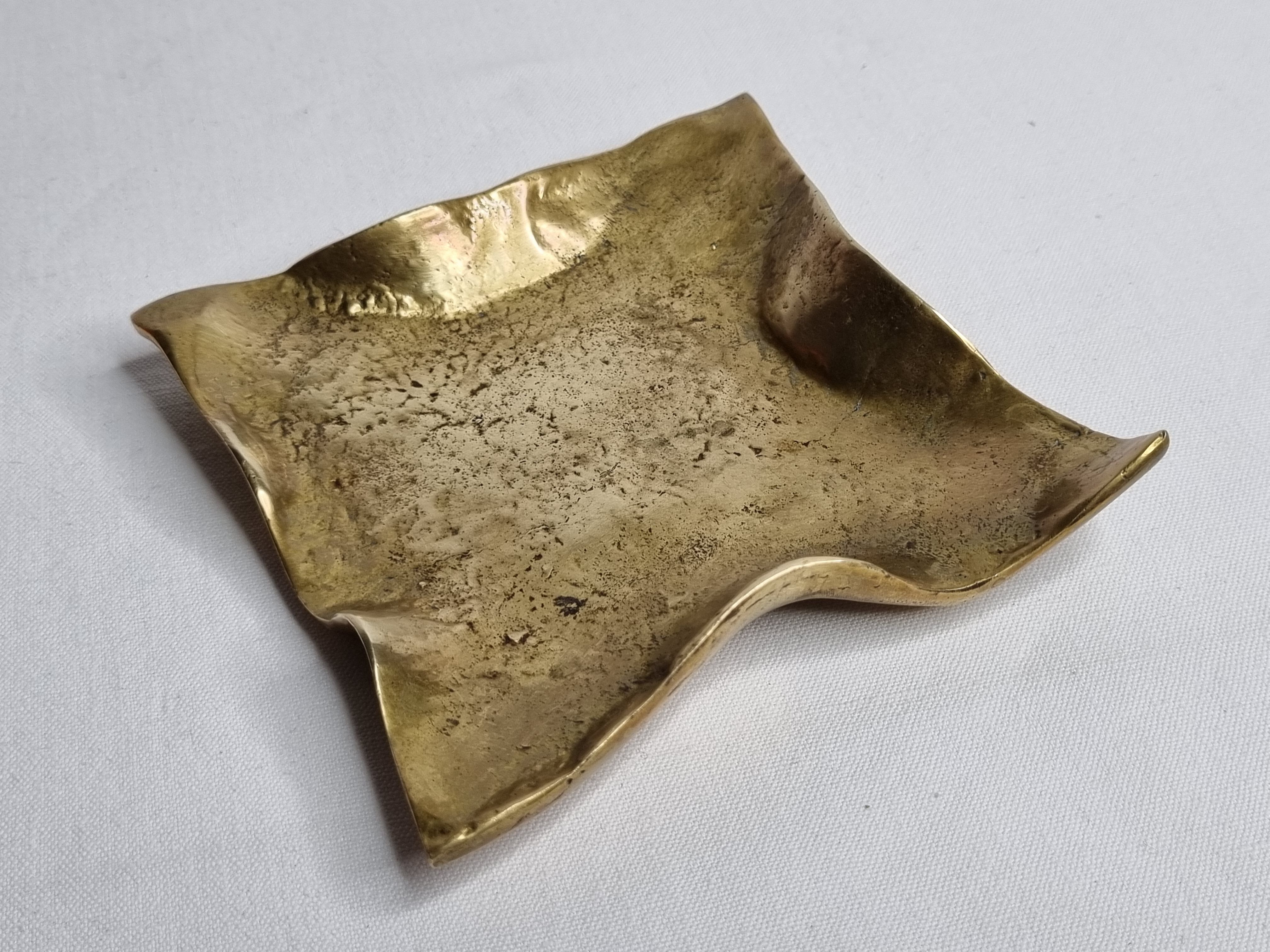 Empty pocket in polished brass representing a crumpled paper, signed CJ, 11.5 cm