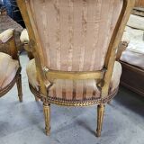 A pair of gilded wooden armchairs in the Louis XVI style.