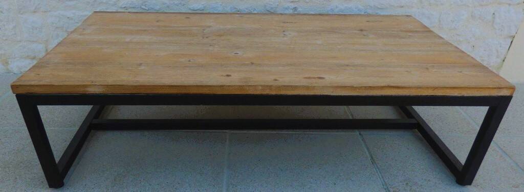 Industrial style coffee table with wooden top supported by a metal base -