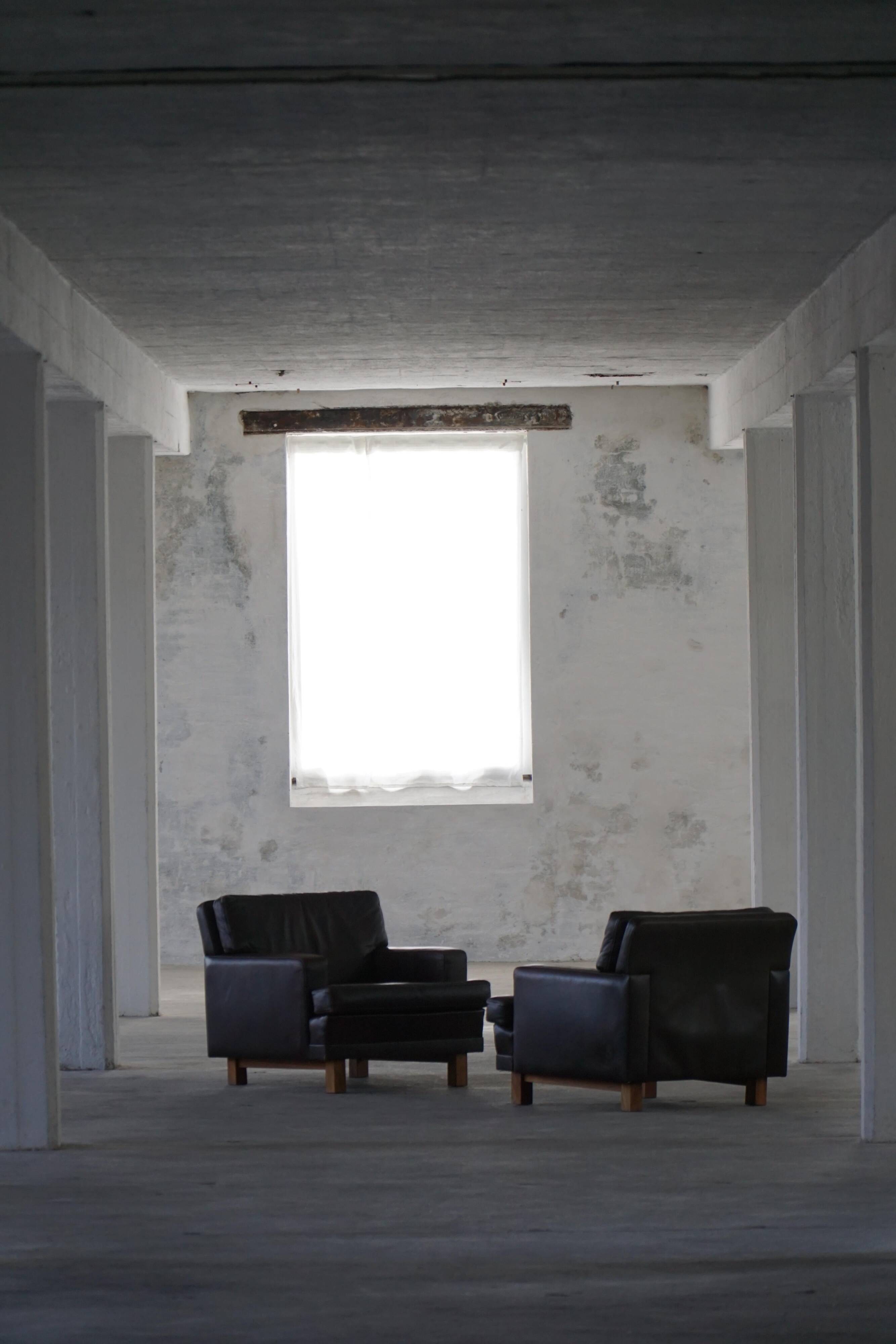 Pair of modern Danish lounge chairs in dark brown leather and rosewood, 1960s.