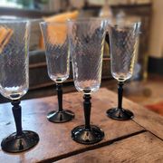 4 clear glass flutes with black stems. 1960–1970. 4 clear glass flutes with black stems.