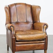 Cognac-colored sheep leather wingback chair finished with black piping