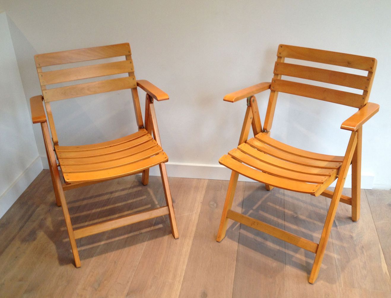Pair of varnished wooden folding armchairs signed Clairitex.