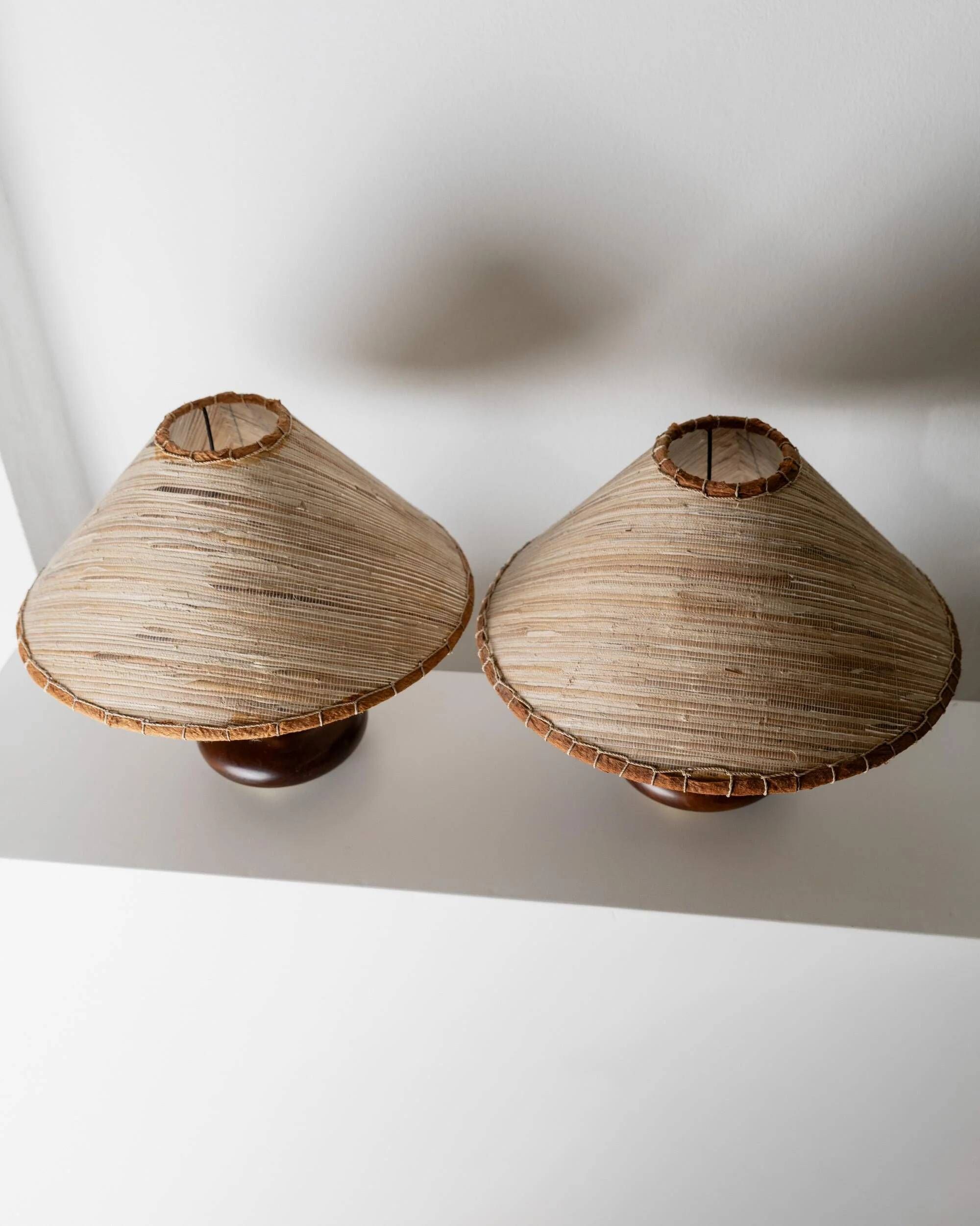 Lot of 2 vintage table lamps from the 1970s, dark wood oval bases with curved brass details, handmade natural fibre lampshades, elegant lighting.
