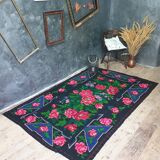 Handwoven floral wool rug, black background with pink roses
