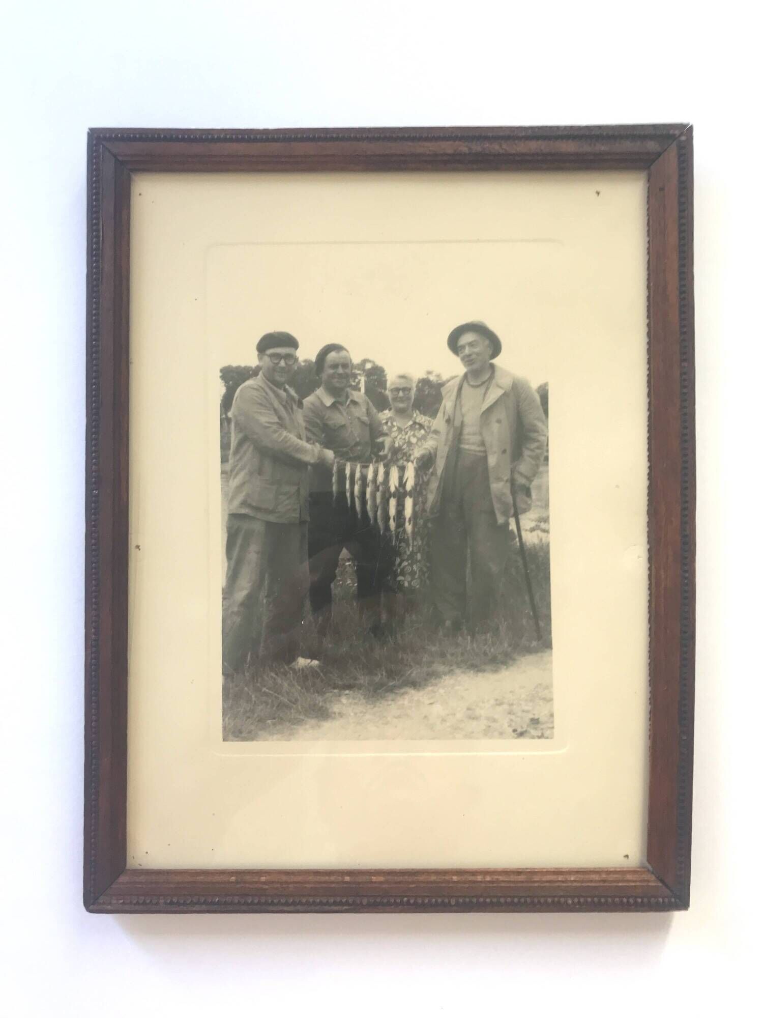 Fishing trophy with radiant faces, c. 1950. Black and white photograph.