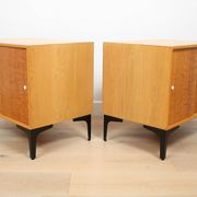 A pair of vintage mid-century bedside tables with oak sliding doors