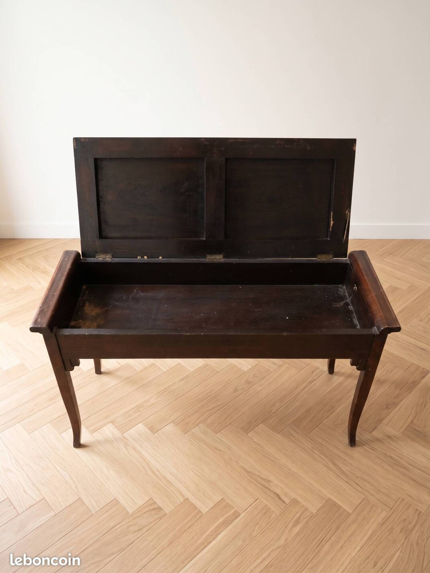 Antique wooden storage bench with red fabric.