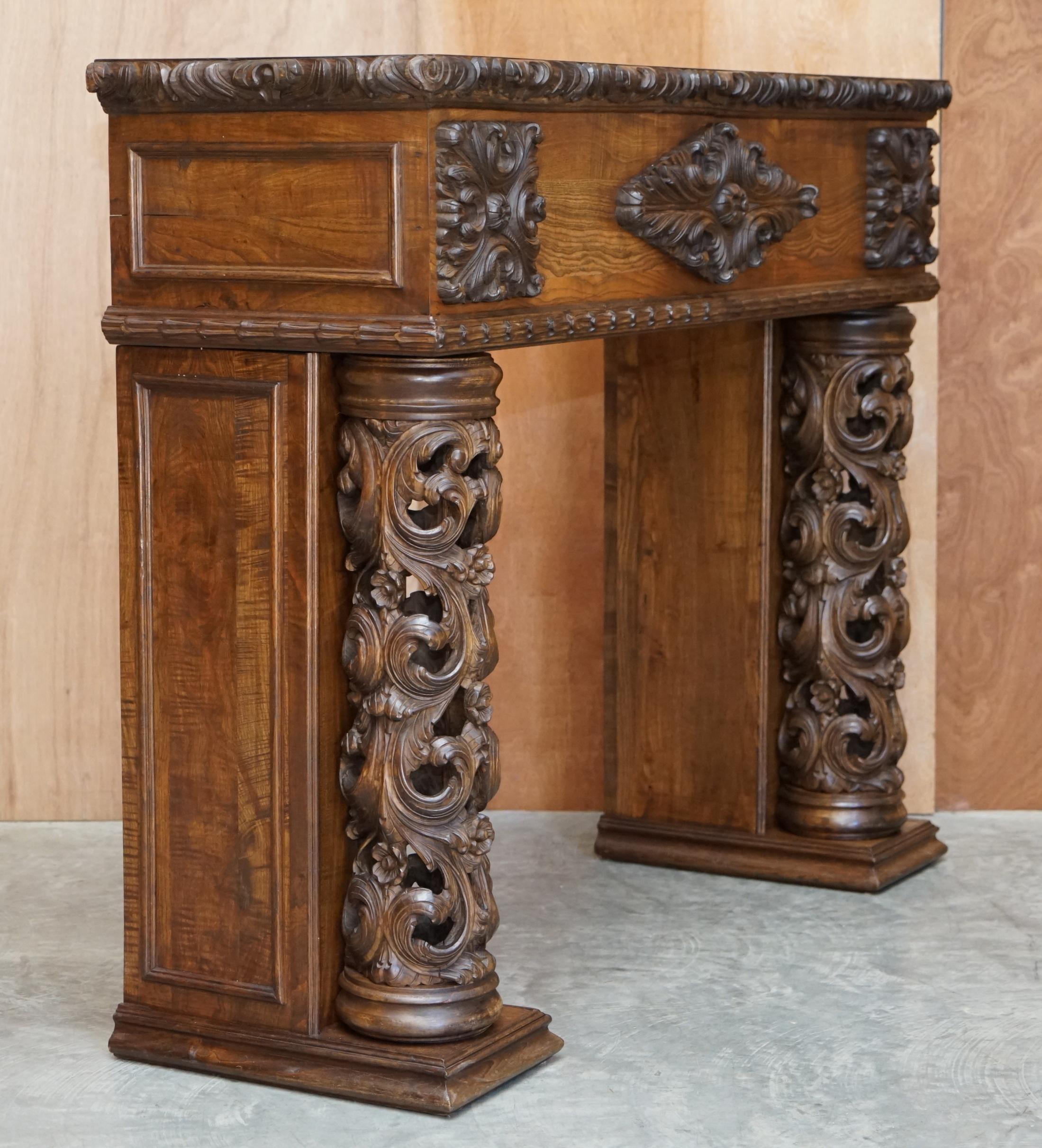 Antique fireplace from around 1880 in solid hand-carved elm with openwork columns.