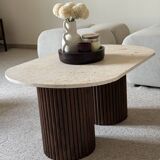 Oval coffee table in travertine and fluted wood.