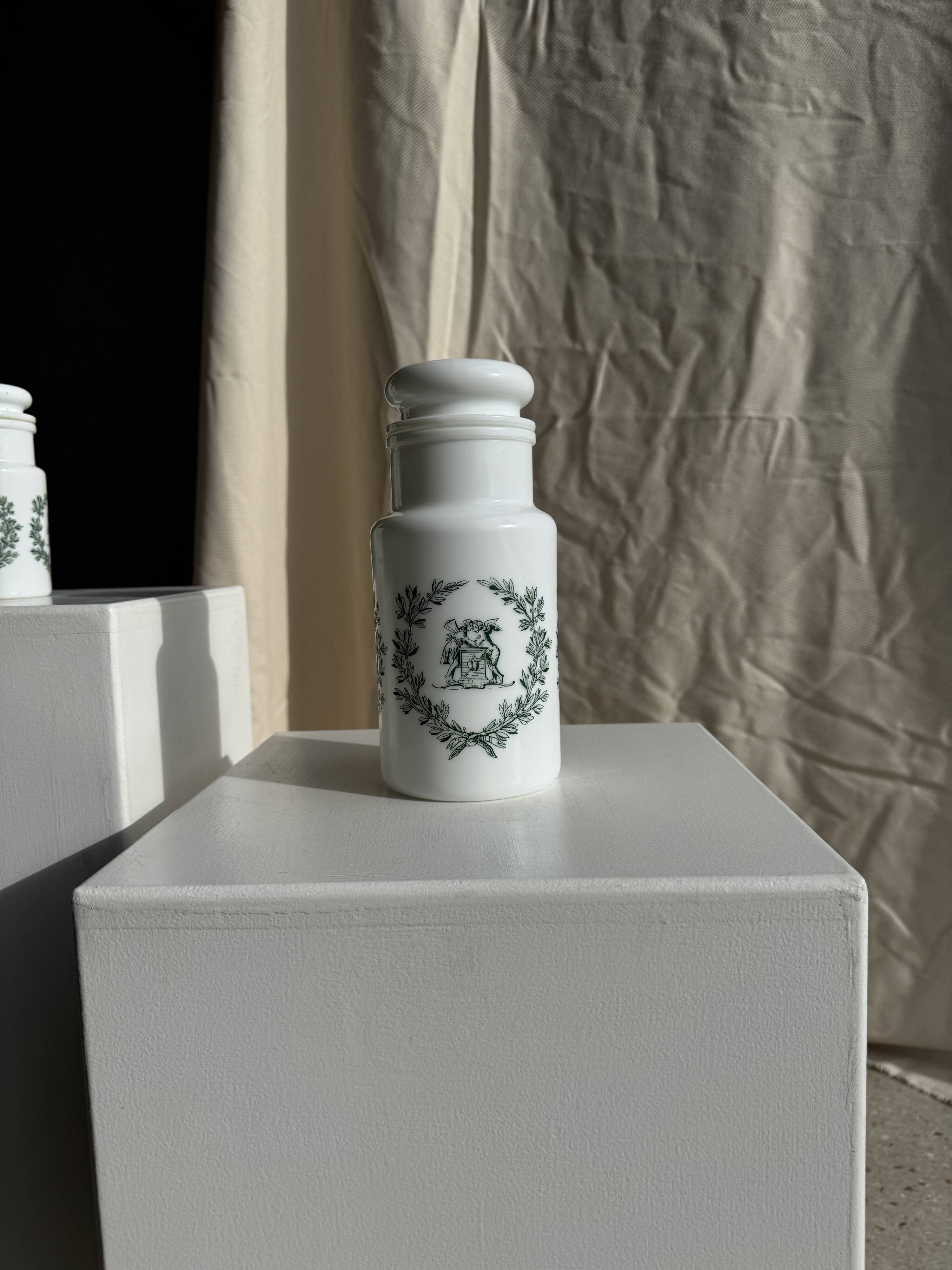 A pair of white glass bottles with Italian green patterns.