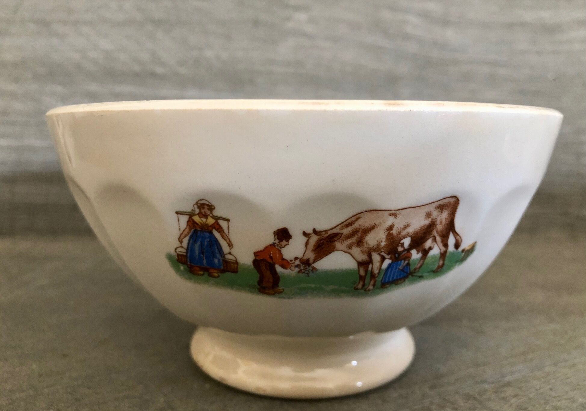 Old bowl decorated with a farmer and her cow
