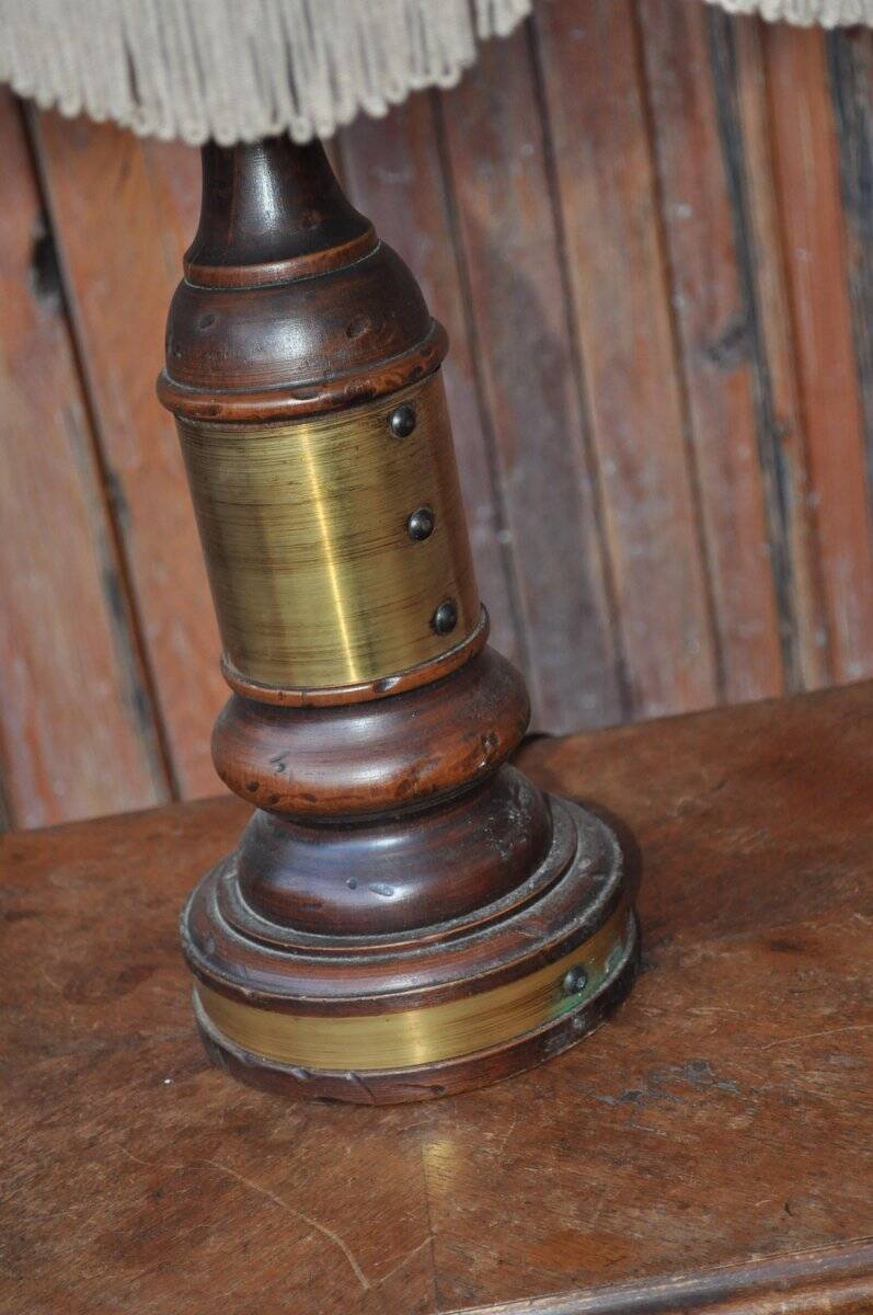 Vintage brown and gold desk lamp made of carved wood and brass, with a fringed shade.