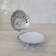 Scallop shell butter dish in stainless steel with its white glass saucer.