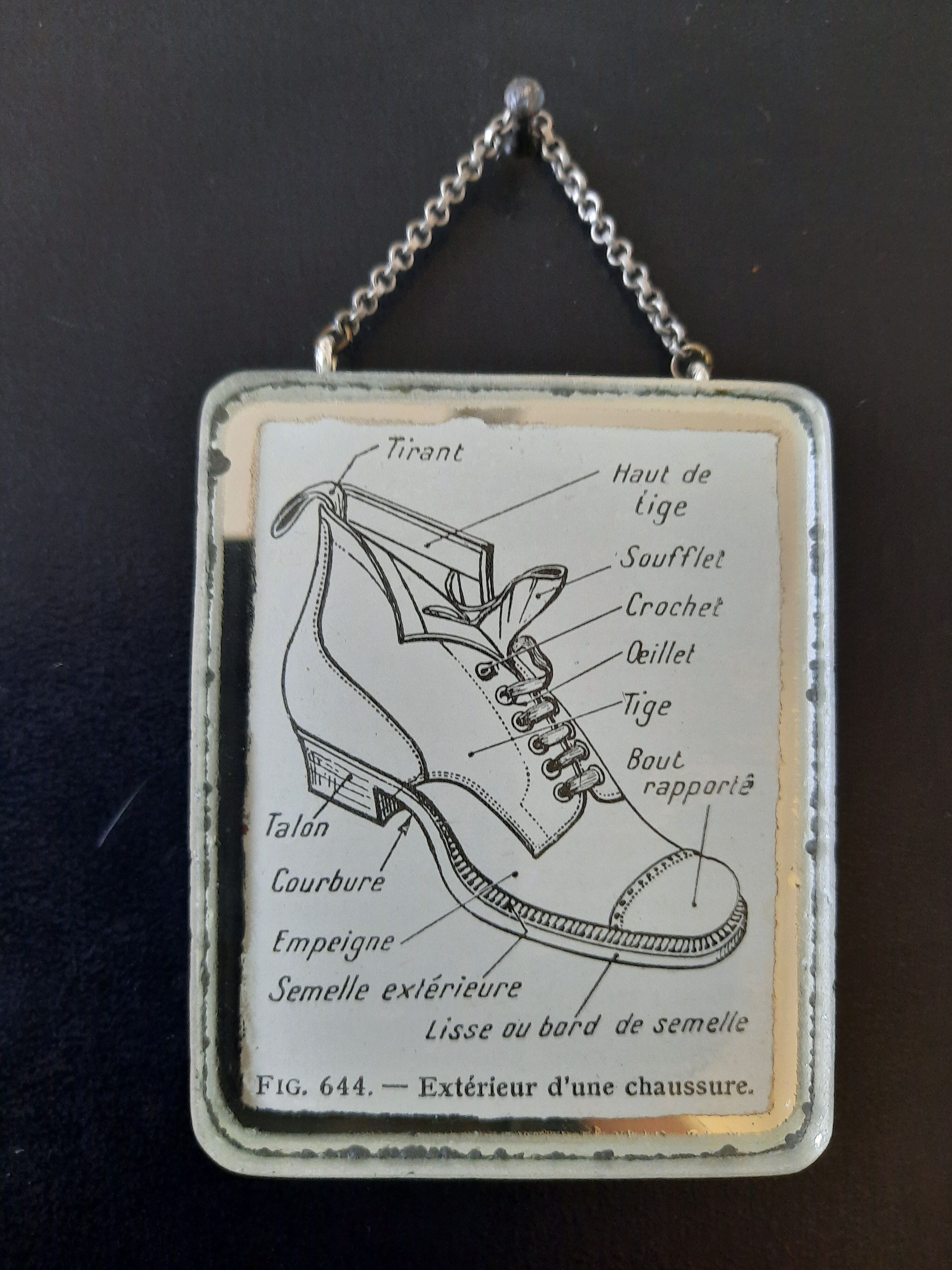 Old illustration "Exterior of a shoe" inserted under mirror