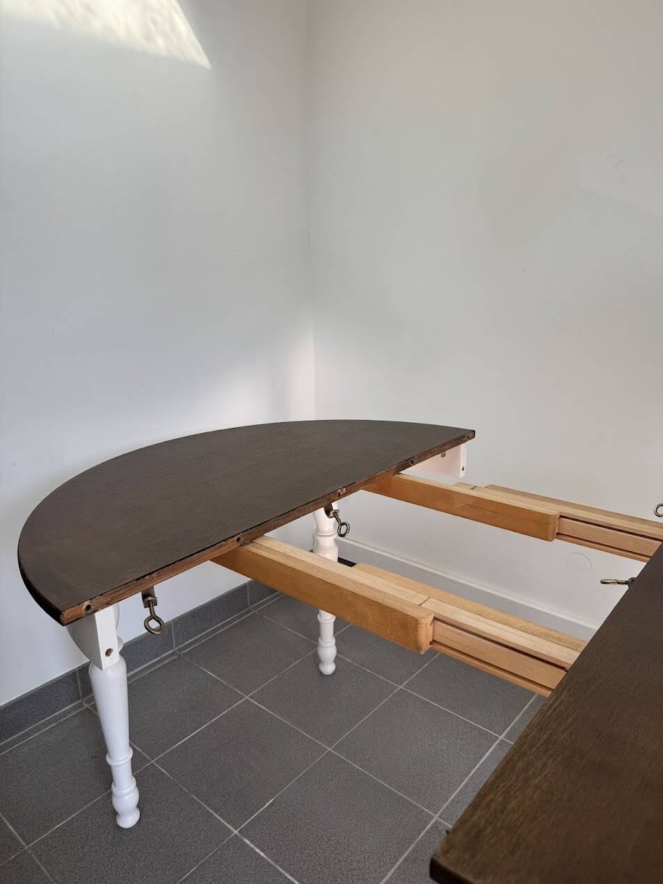 Restored solid wood round table with integrated extensions.