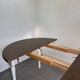 Restored solid wood round table with integrated extensions.