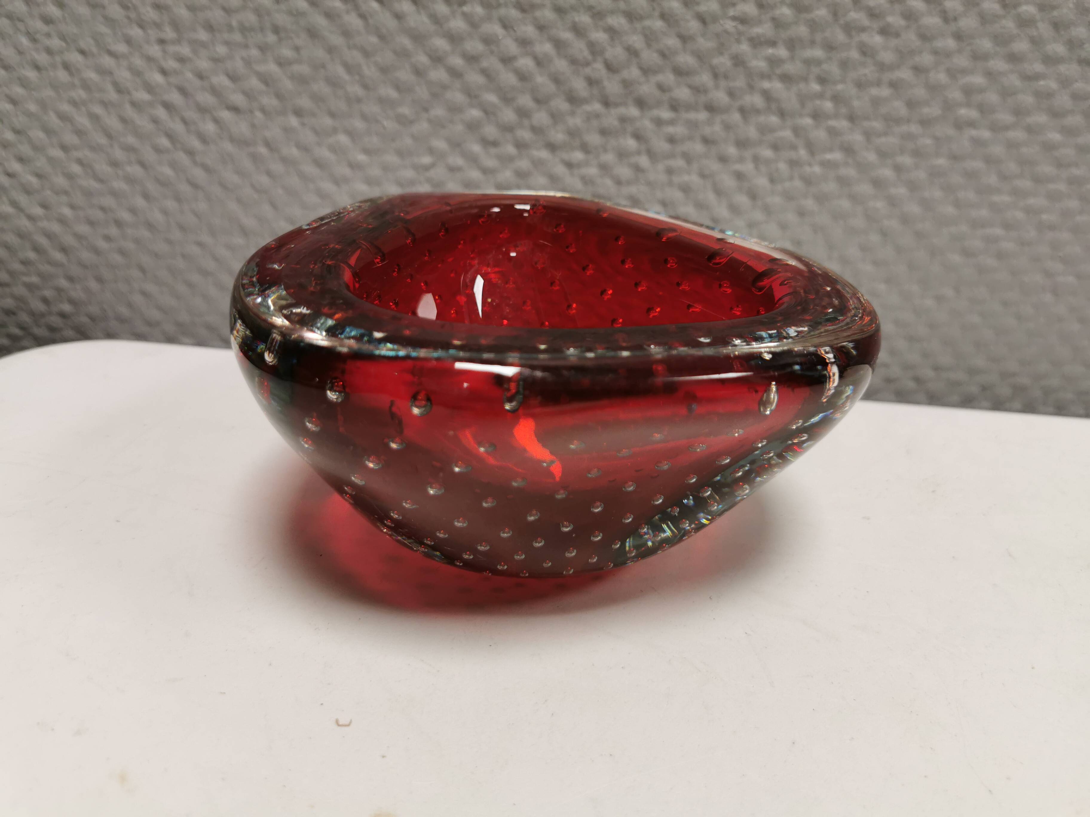 Small glass bowl in beautiful emerald red color with inlaid bubbles.