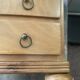 Blonde wooden doll's chest with brass handles.