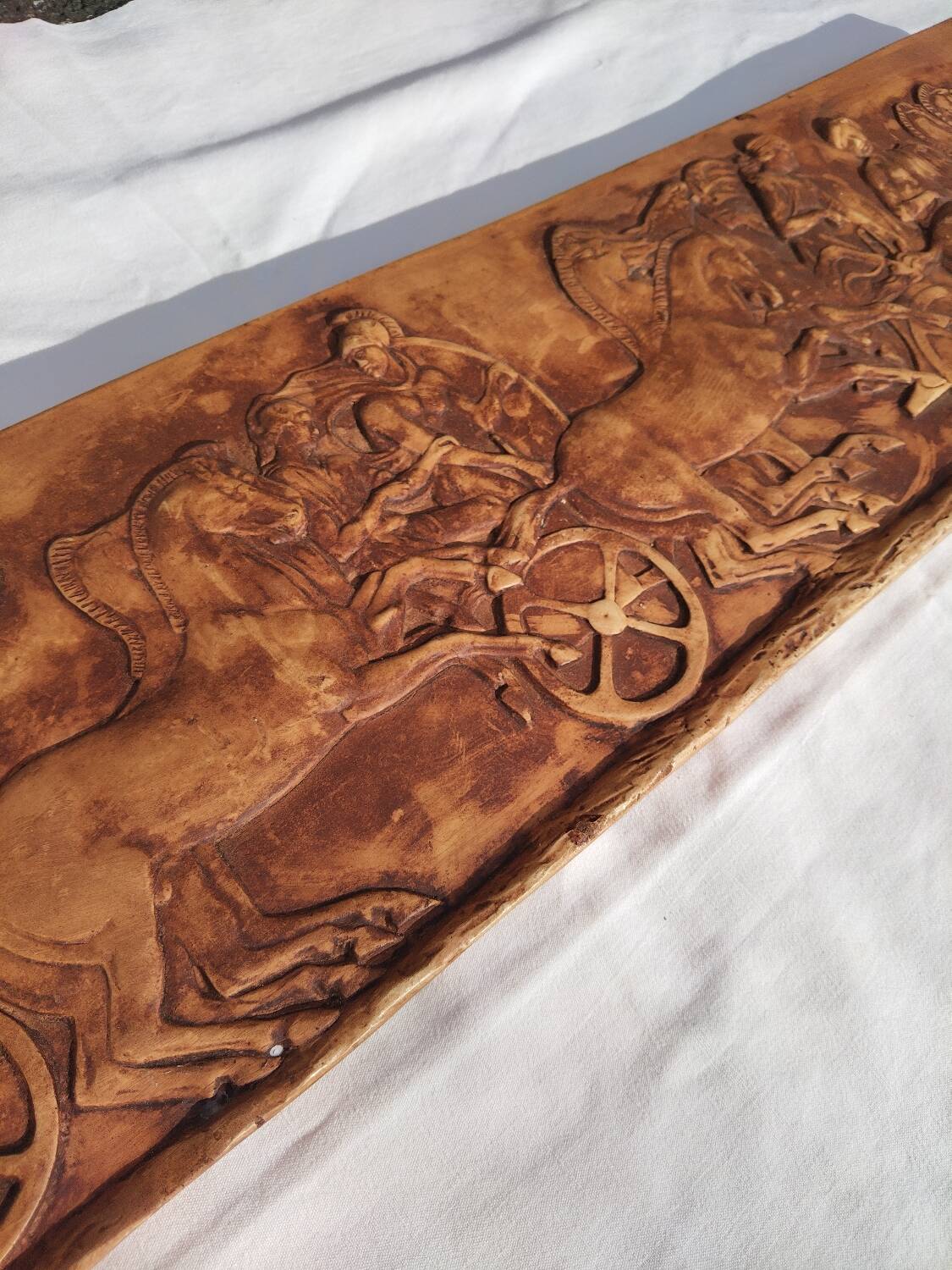 Bas-relief plaster scene of horses and a cart.