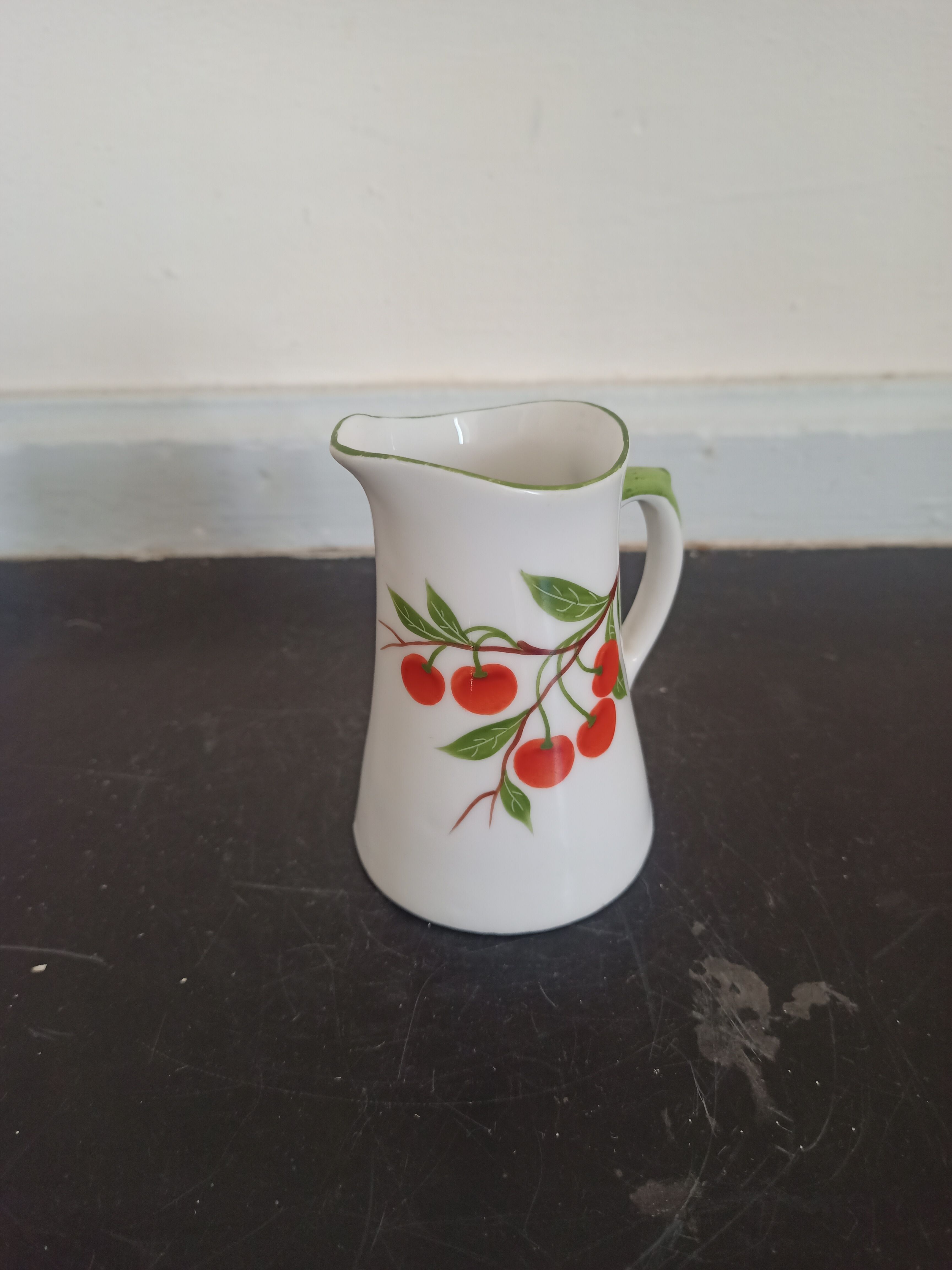 Small ancient porcelain pitcher decorated with cherries