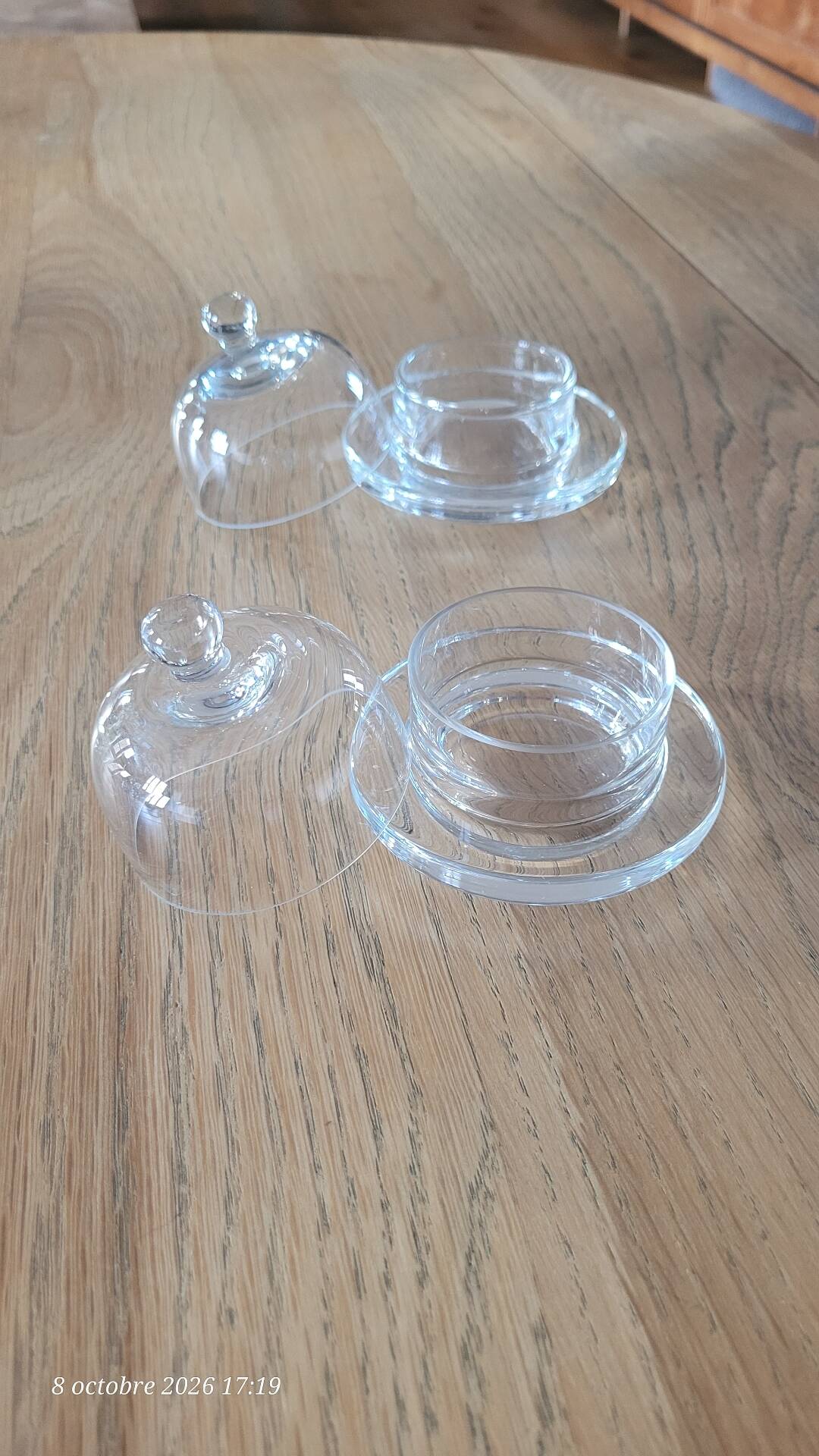 2 transparent glass butter dishes with their matching cloches.