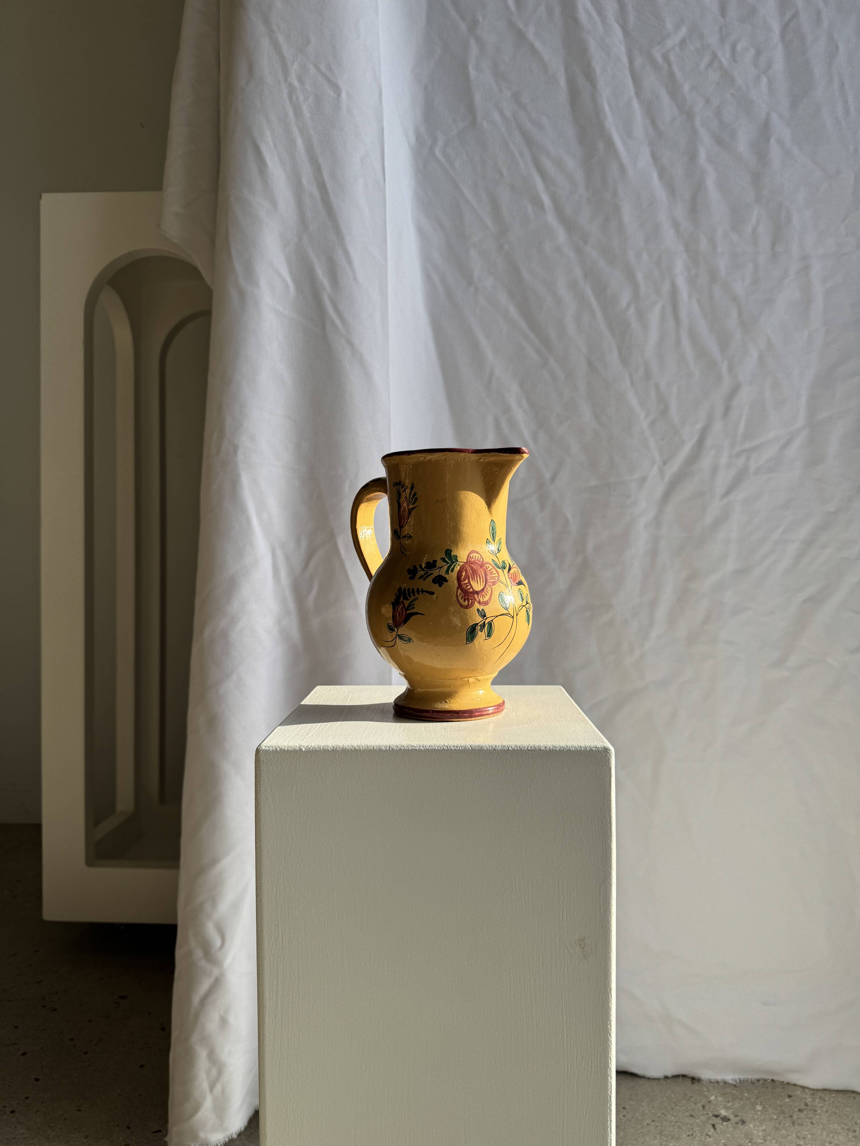 Large antique handmade ochre yellow jug with a pink flower pattern.
