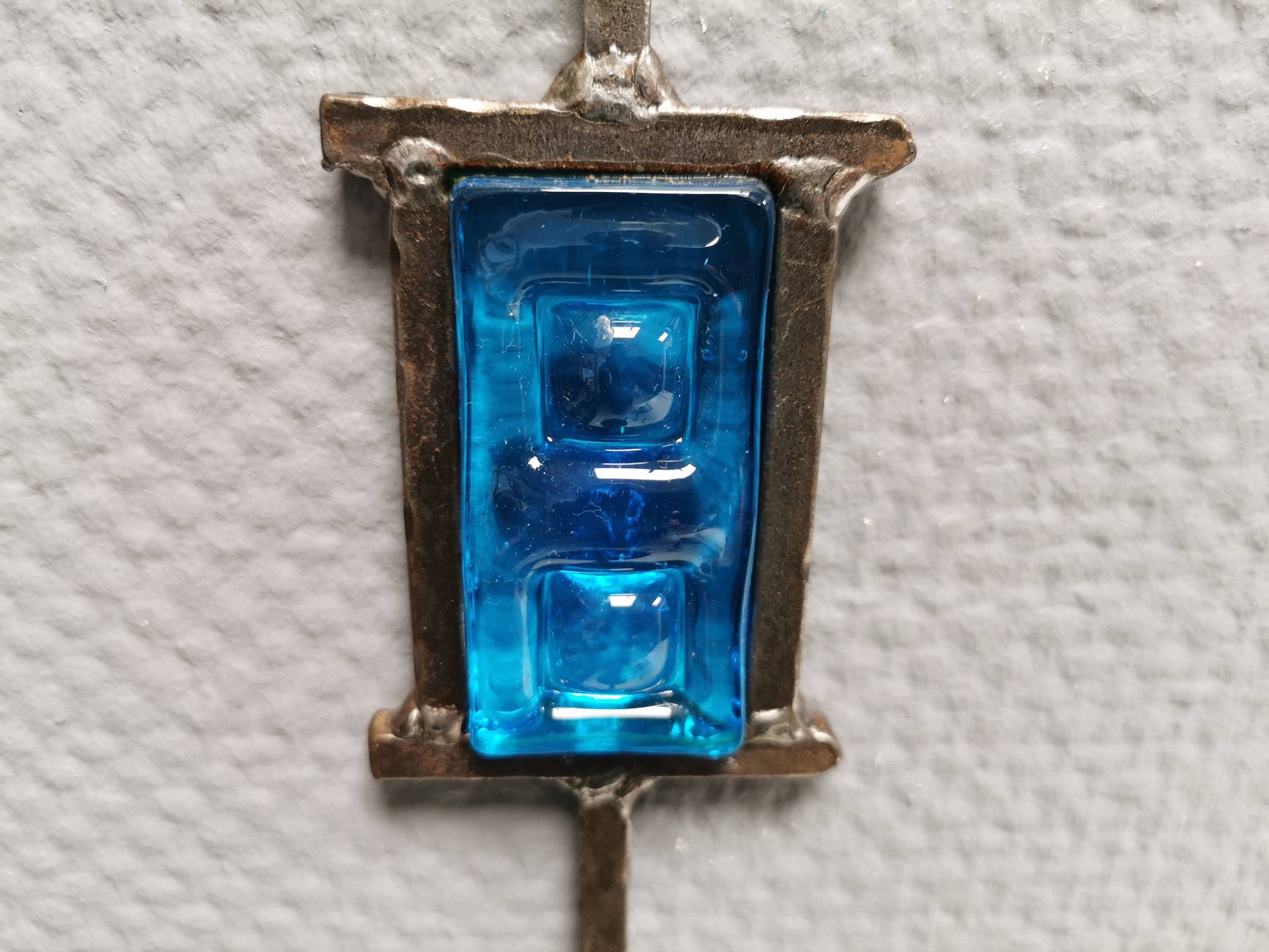 Wall-mounted candle holder in cast iron and hard pressed blue glass.