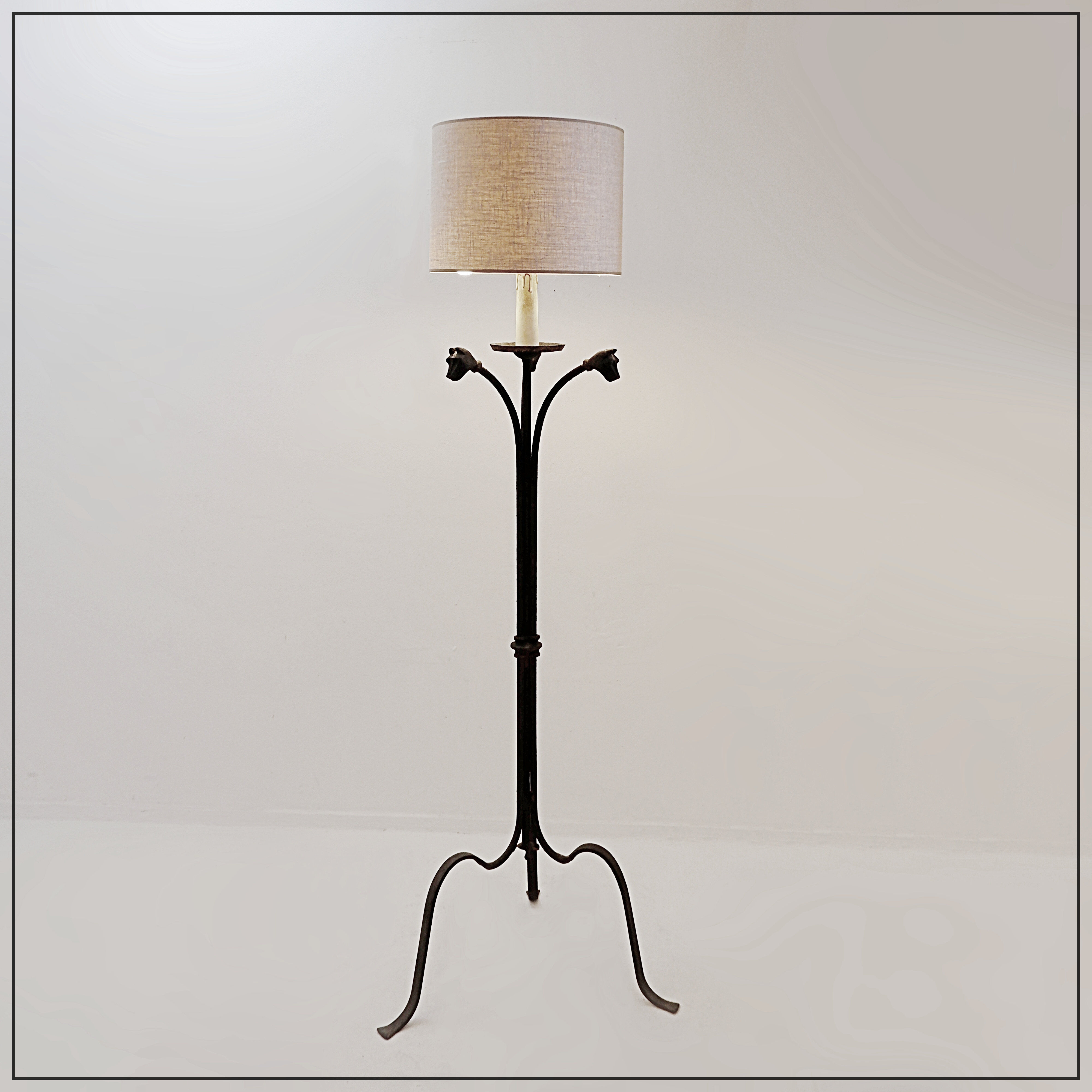 Wrought iron tripod floor lamp decorated with stylized animal heads
