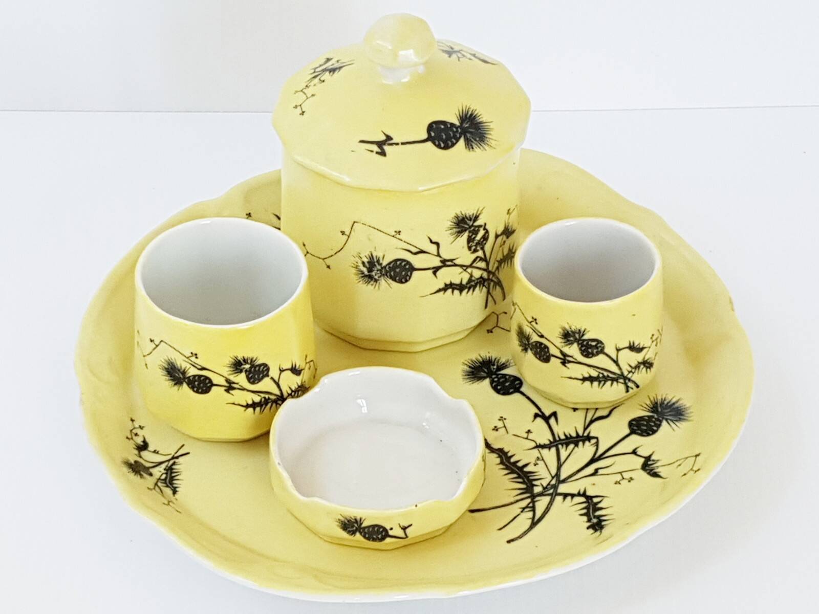 A yellow Art Deco ceramic tobacco service decorated with thistles from the 1920s to 1930s.