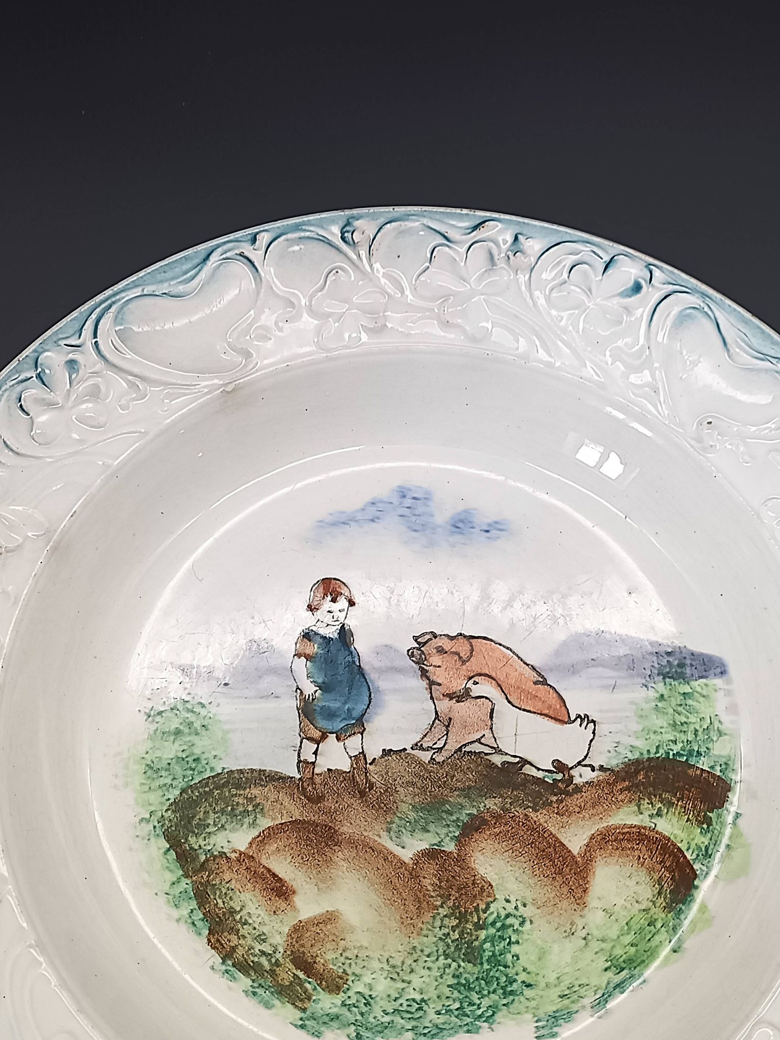 Large antique hollow dish from the 19th century, earthenware with pastoral decoration featuring a child, pig, and goose.