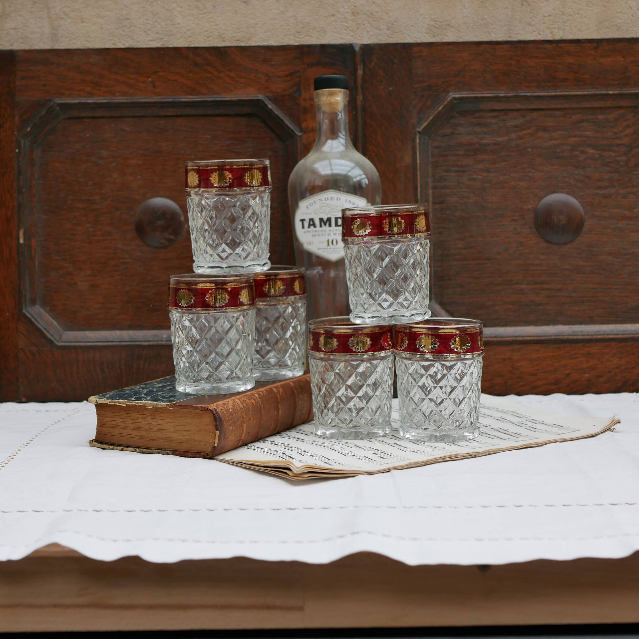 Six pressed glass whisky glasses with red and gold rims